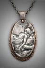 Oval pendant of bronze on copper; fine texture background; 1” x 2”; chain 18”with the image of a reclining woman; L= 2”  W= 1”.