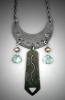 Steel Crescent Pendant –Aqua-crystal; L=  2 ½”   W= 1 3/8”;   Hand sculpted steel crescent pendant.  From the Steel crescent hangs a 1 ½” steel rectangle flanked by two 8x8mm Aqua-crystal briolette gemstones and solid bronze beads.  Hangs on a 26” chain.